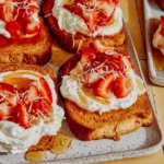 A platter of honey brick toast topped with strawberries and whipped cream.