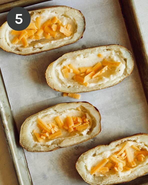 Cheese added into potato halves.
