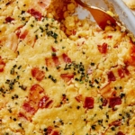 Corn casserole recipe with some scooped out on a plate.