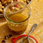 Freshly made Italian vinaigrette dressing in a jar with the lid next to it.