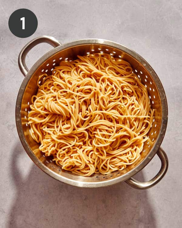 A colander with cooked spaghetti noodles in it.