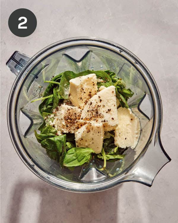 A blender with ingredients in it to make Tallarines Verde.