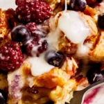 Berry bread pudding with a glaze being spooned on top.