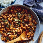 Cashew chicken recipe in a skillet with rice on the side.