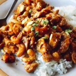 Cashew chicken with on two plates with forks and rice.