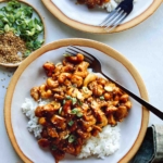 Cashew chicken with on two plates with forks and rice.