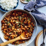 Cashew chicken recipe in a skillet with rice on the side.