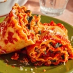 Close up on a plate of two lasagna roll ups.