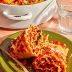 A close up shot of two lasagna roll ups on a plate about to be eaten.