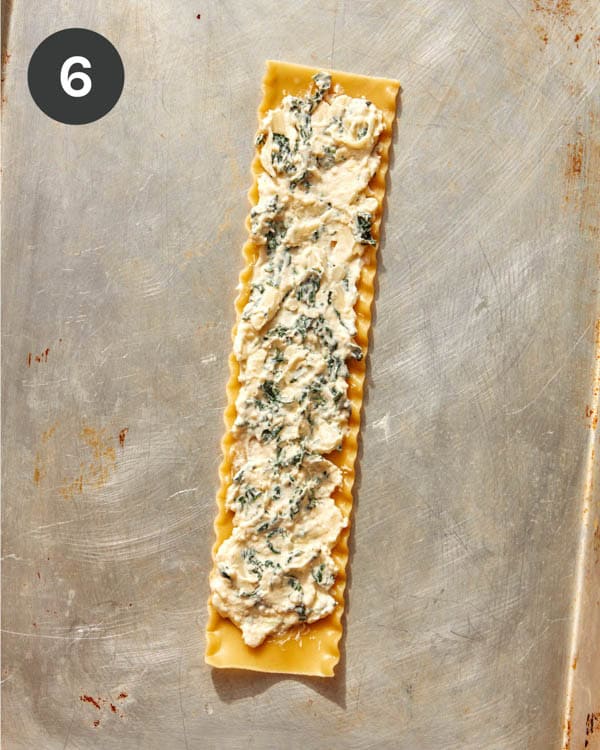 A sheet of lasagna with ricotta mixture spread on it.