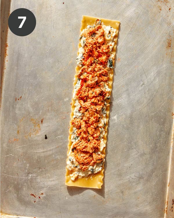 A sheet of lasagna with ricotta and a ground turkey mixture spread on it.
