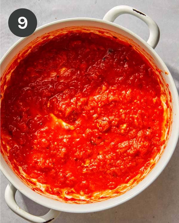 A baking dish with some marinara spread on the bottom of it.