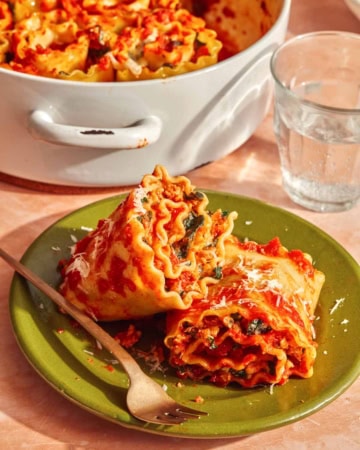 A close up shot of two lasagna roll ups on a plate about to be eaten.