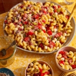 Pasta salad being served into small bowls.