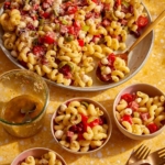 Pasta salad being served into small bowls.