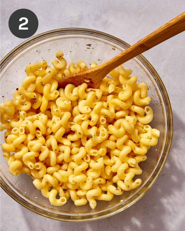 Pasta in a glass bowl mixed with Italian vinaigrette.