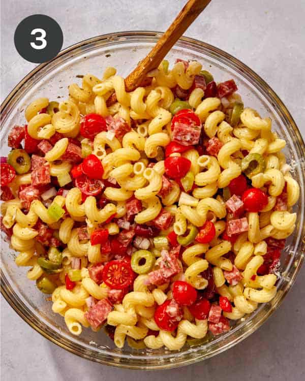 Pasta salad being mixed in a bowl.