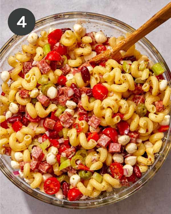 Pasta salad being mixed in a bowl.