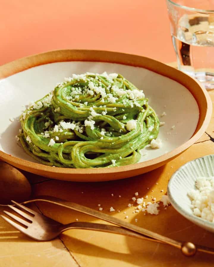 Tallarines Verde in a bowl with queso fresco on top.