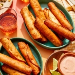 Flautas freshly made in some bowls with a dipping sauce on the side.