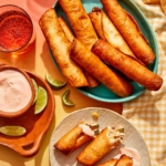 Freshly made Flautas recipe with one torn in half on a plate with some dipping sauce.