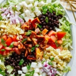 Loaded BBQ chicken salad on a plate with dressing on the side.