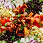 Loaded BBQ chicken salad on a plate with dressing on the side.