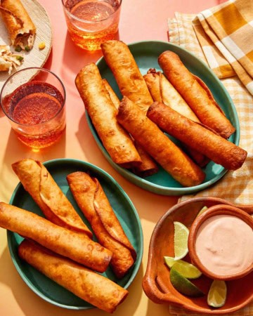 Flautas freshly made in some bowls with a dipping sauce on the side.