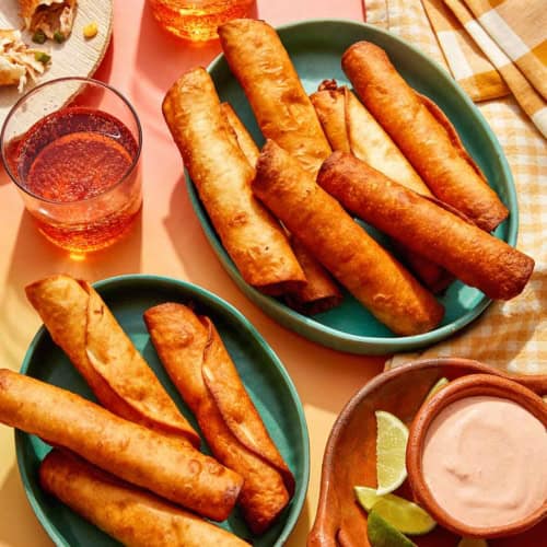 Flautas freshly made in some bowls with a dipping sauce on the side.