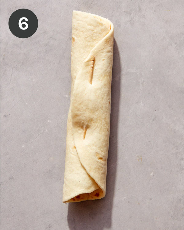 A flauta rolled up and secured with a toothpick.