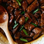 Mongolian beef in a skillet with green onions.