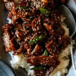 Mongolian Beef on a platter over rice with a spoon in it.