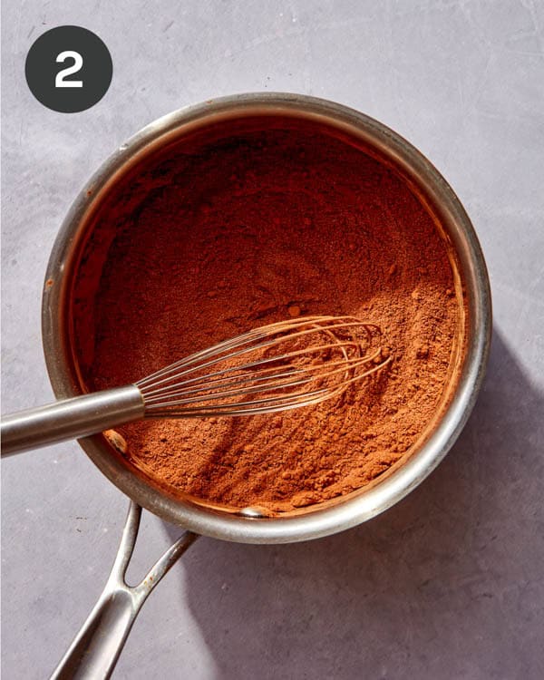 Dry ingredients for a chocolate sauce whisked together in a pot.