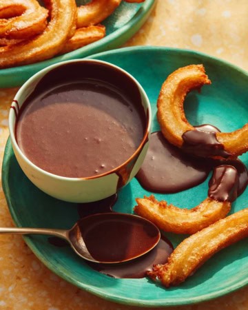 A plate with churros and a bowl of homemade chocolate sauce.