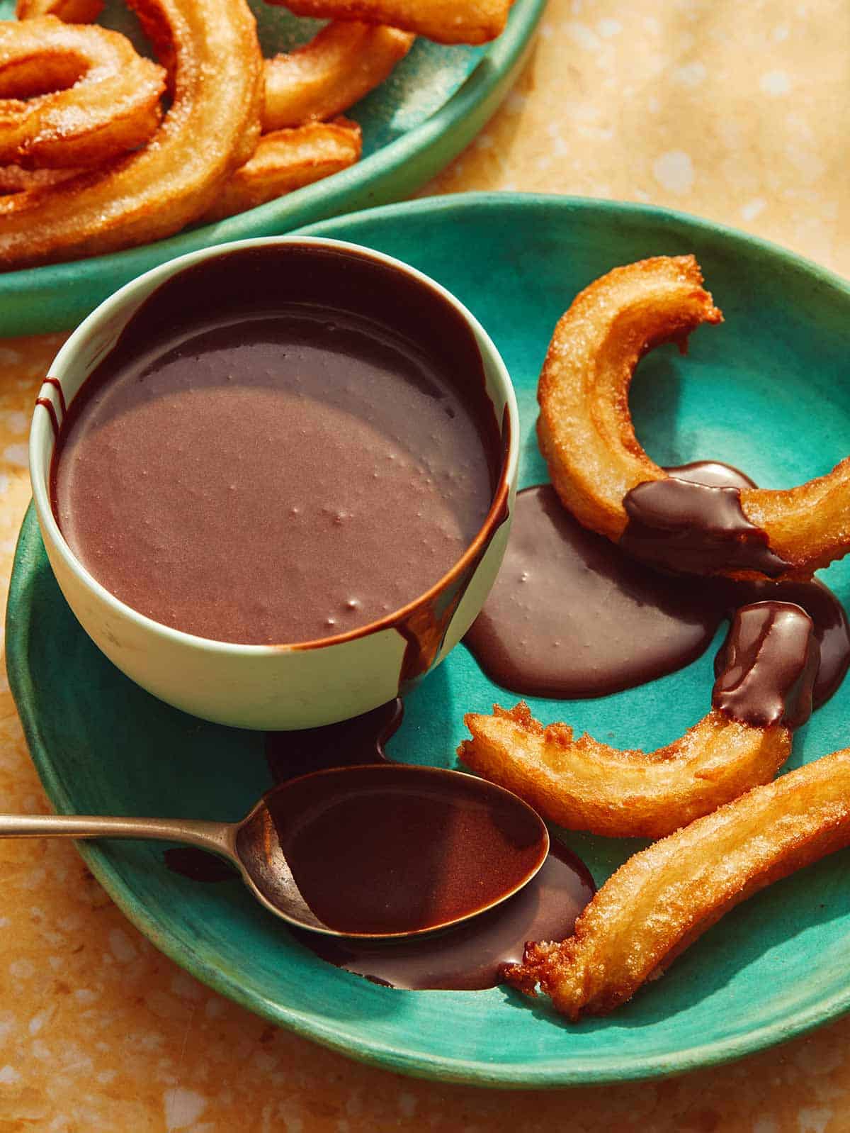 A plate with churros and a bowl of homemade chocolate sauce.
