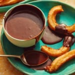A plate with churros and a bowl of homemade chocolate sauce.
