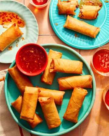 Vietnamese spring rolls on a platter with a bowl on sweet chili sauce.