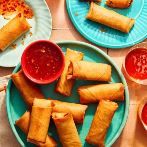 Vietnamese spring rolls on a platter with a bowl on sweet chili sauce.