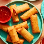 Vietnamese spring rolls on a platter with a bowl on sweet chili sauce.