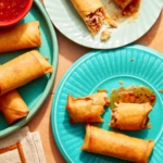 Three plates of partially eaten spring rolls and sauce.