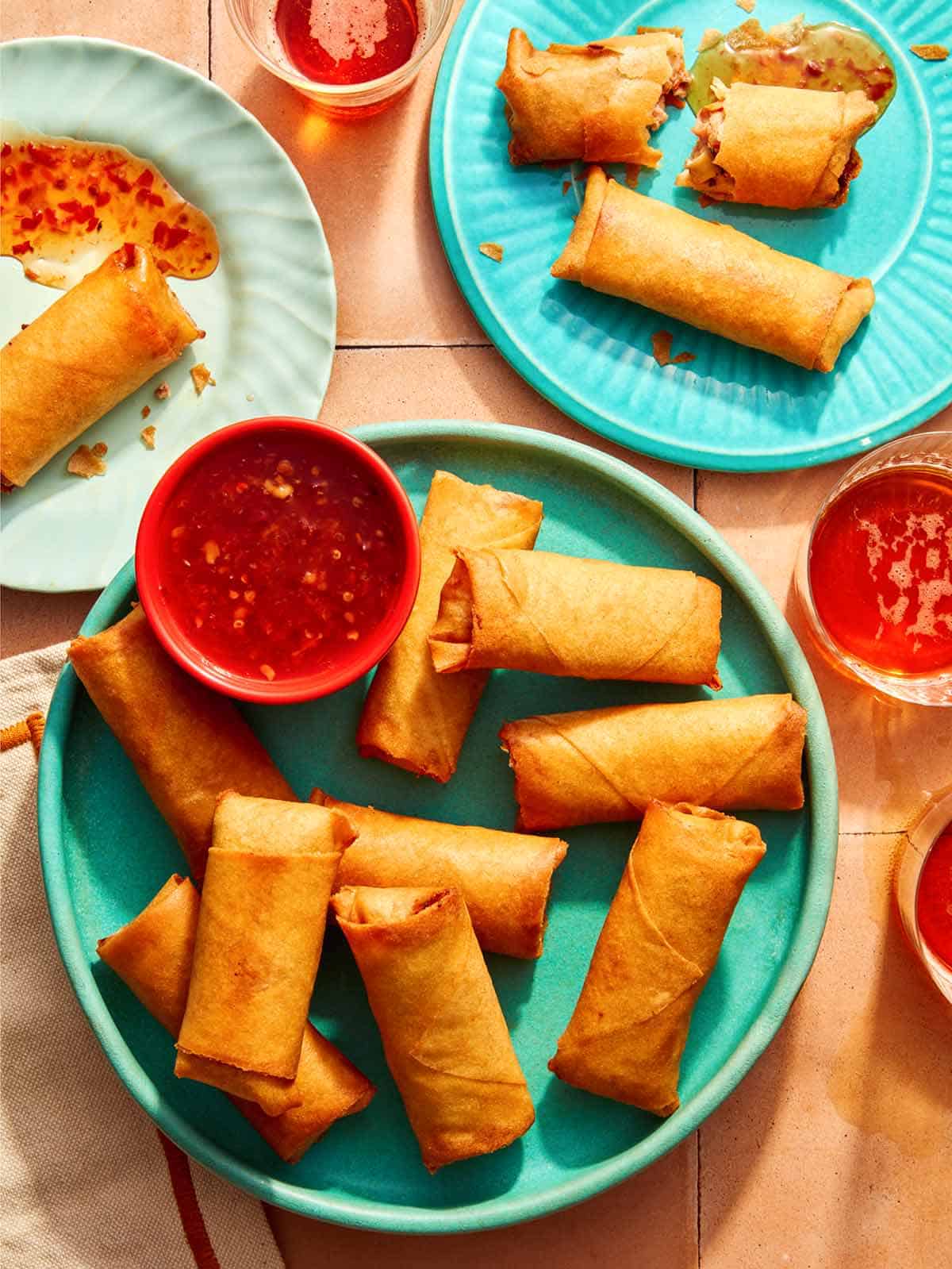 Vietnamese spring rolls on a platter with a bowl on sweet chili sauce.