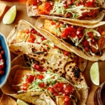 Baja fish tacos on a board with lime wedges around them.