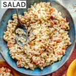 Hawaiian style macaroni salad in a bowl with serving bowls nearby.