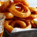 Beer battered fried onion rings with ranch dressing and beer on the side.