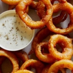 Close up on beer battered onion rings with ranch.