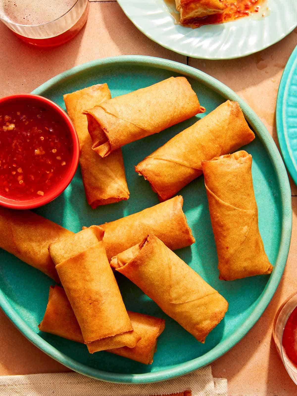 Vietnamese spring rolls on a platter with a bowl on sweet chili sauce.
