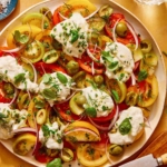 Tomato salad on a plate with herbs on the side.