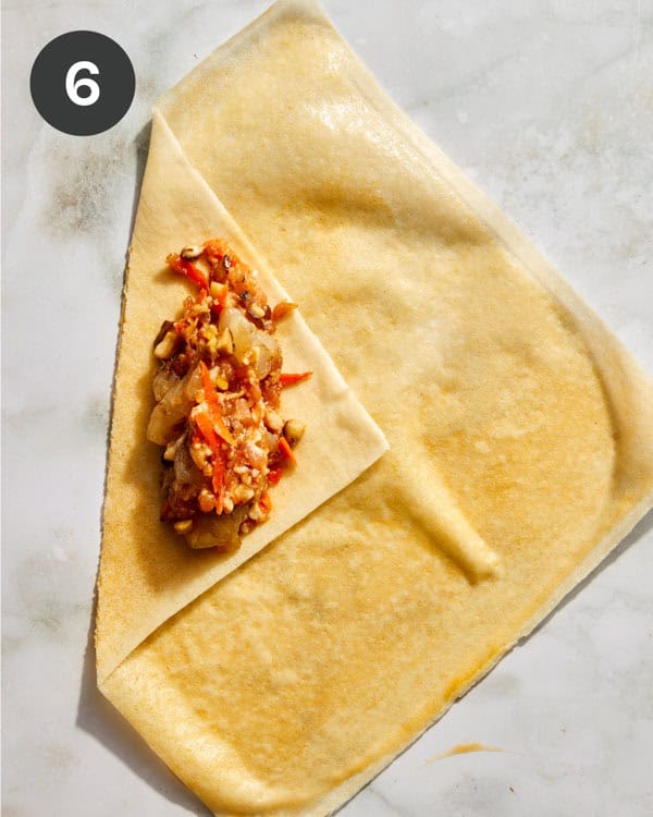 A spring roll wrapper with filling on it about to be rolled up.