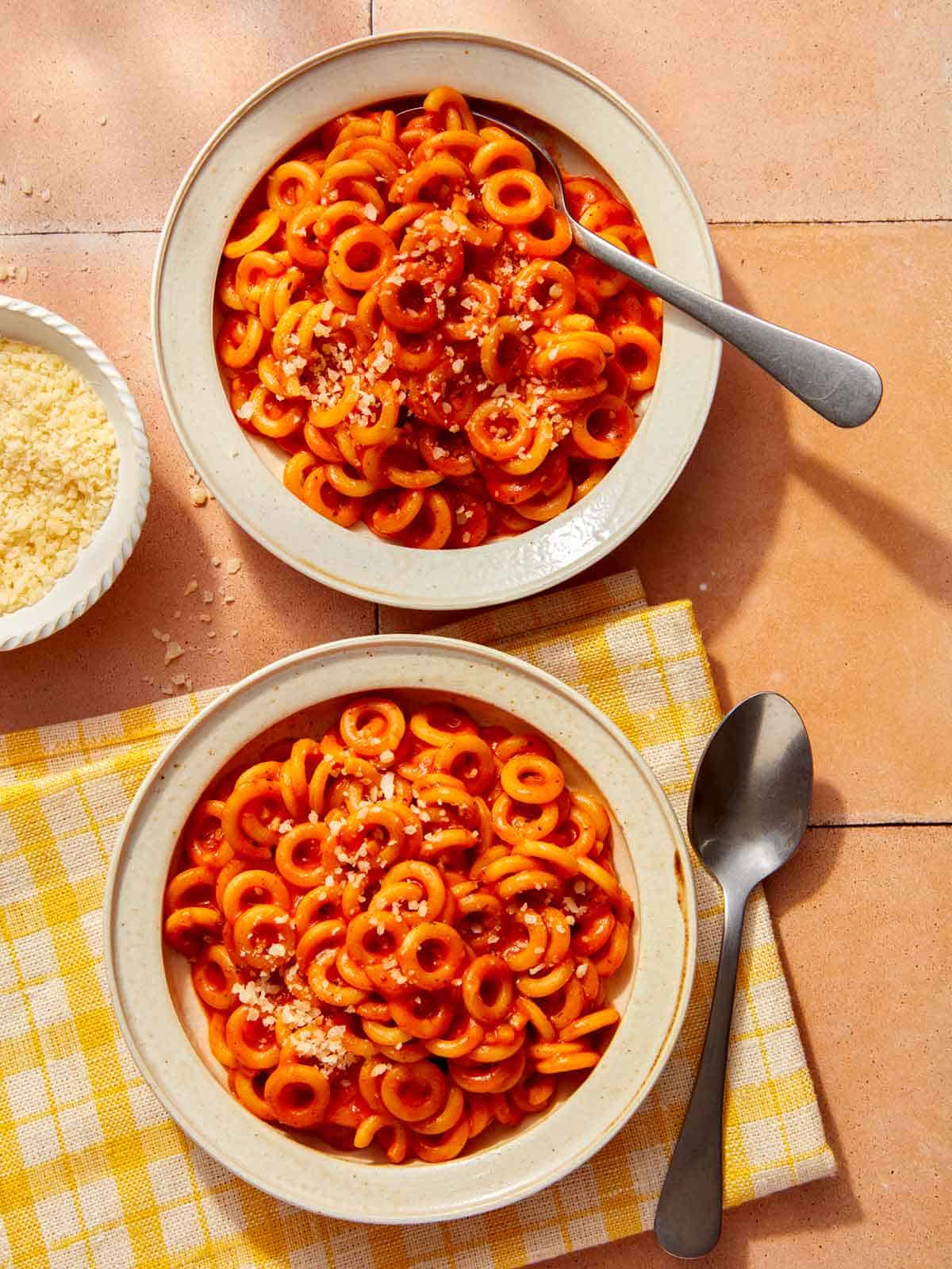 Homemade Spaghetti Os in two bowl with parmesan on the side.