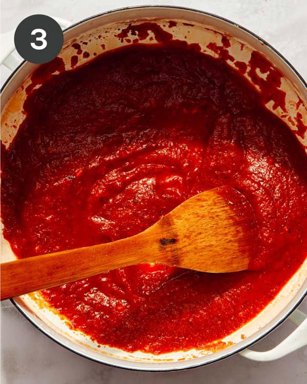 Tomato sauce and paste with seasoning being cooked down.